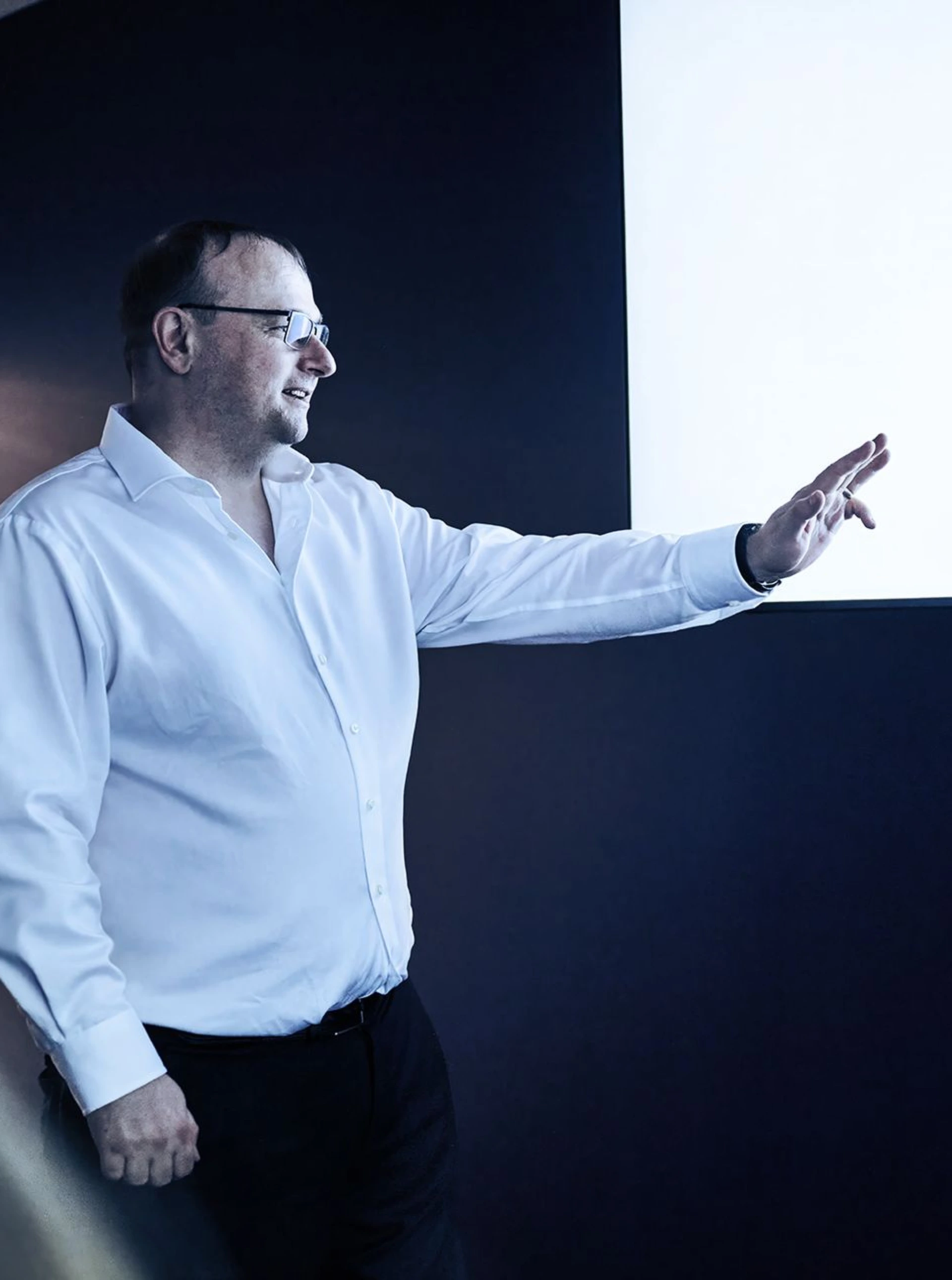 Man in white shirt presenting to someone pointing at a projection screen displaying a list of notes and EAP protocols. Presentation setting with dark background and doorway.