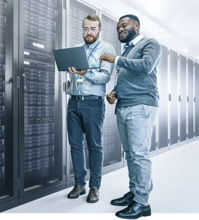 Two men looking at laptop in front of server wall